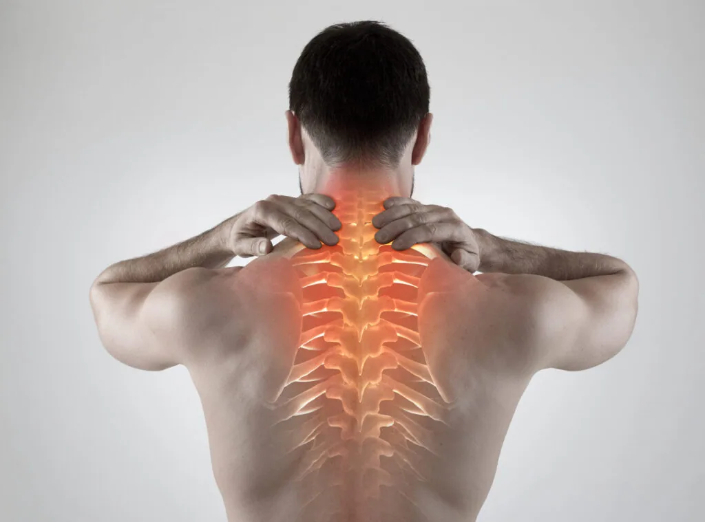 Man from behind with hands on neck, showing glowing orange spine and nerve overlay indicating pain